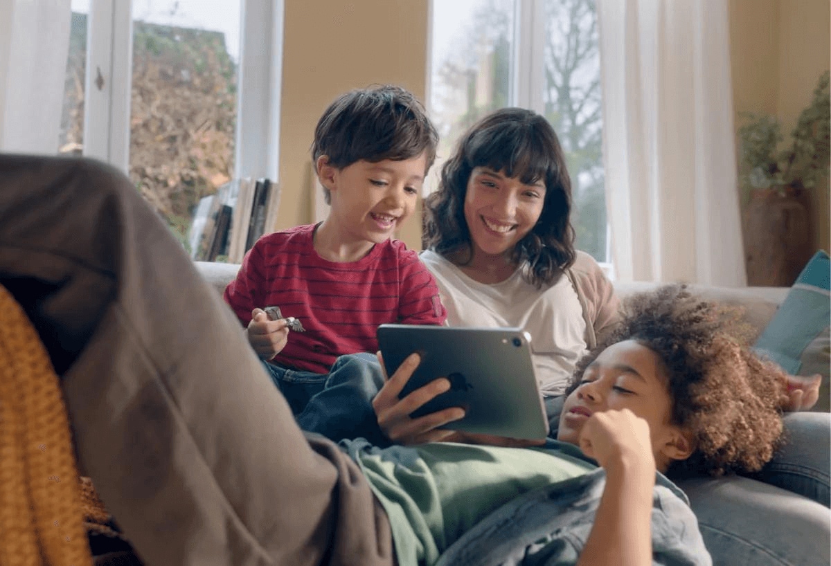 Dos niños jugando en un iPad con una mujer mayor