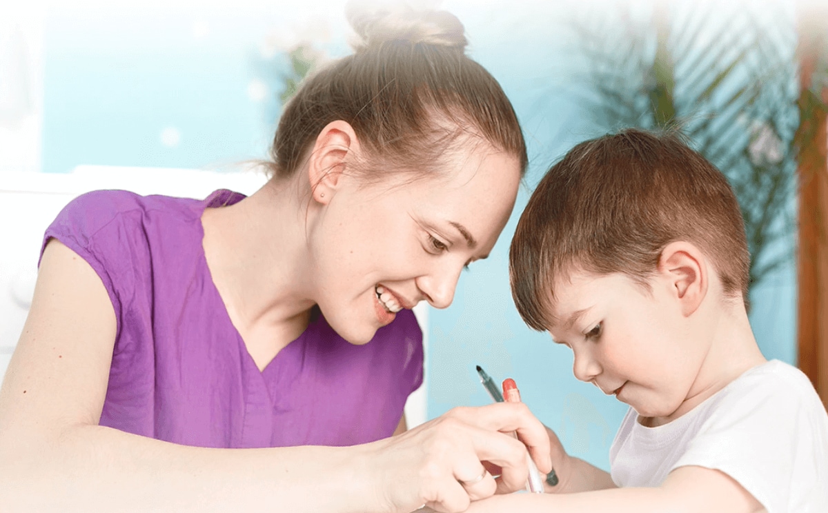 Primer plano de los rostros de una mujer y un niño que dibujan sonriendo