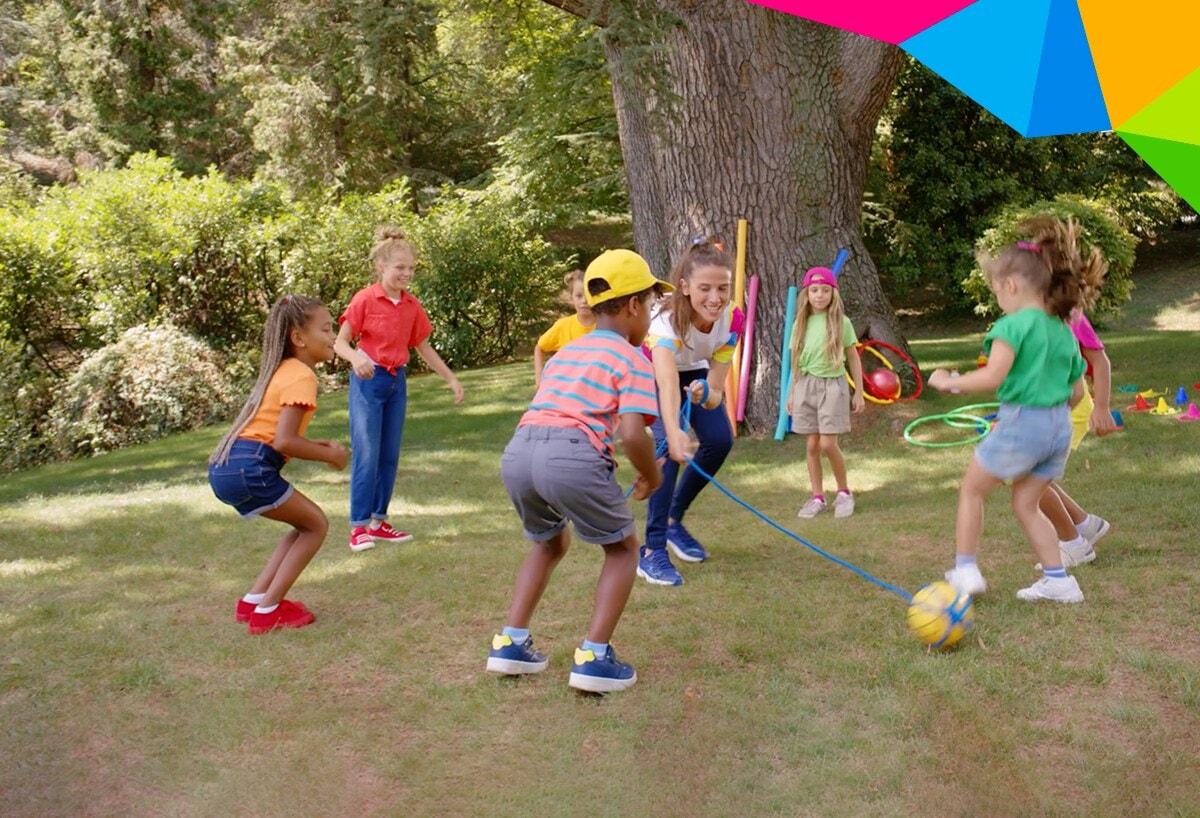 Kids playing with a yellow ball around an female instructor