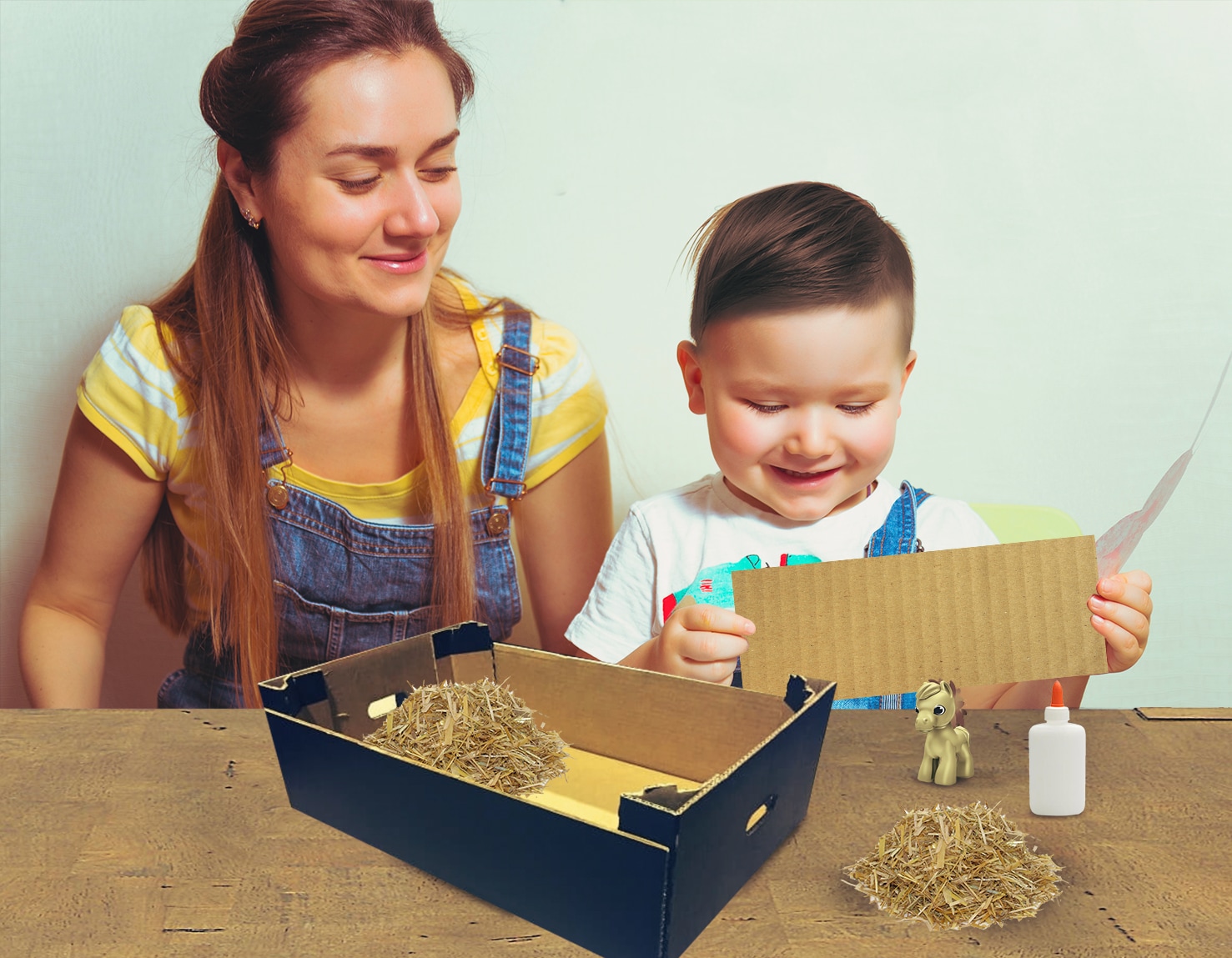 Mamá y niño pequeño, sonrientes, realizando manualidades sobre una mesa con pegamento y Kinder Sorpresa.