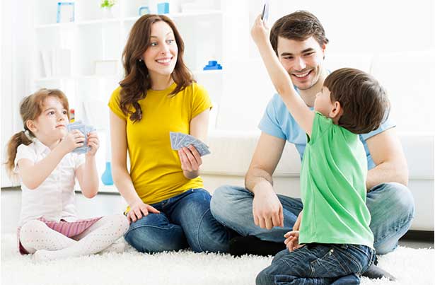 Mamá y papá jugando con cartas con un niño.