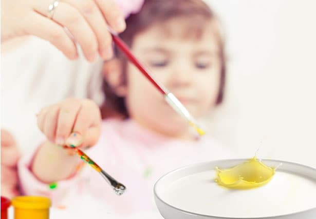 Niña pequeña utilizando pinturas y pinceles