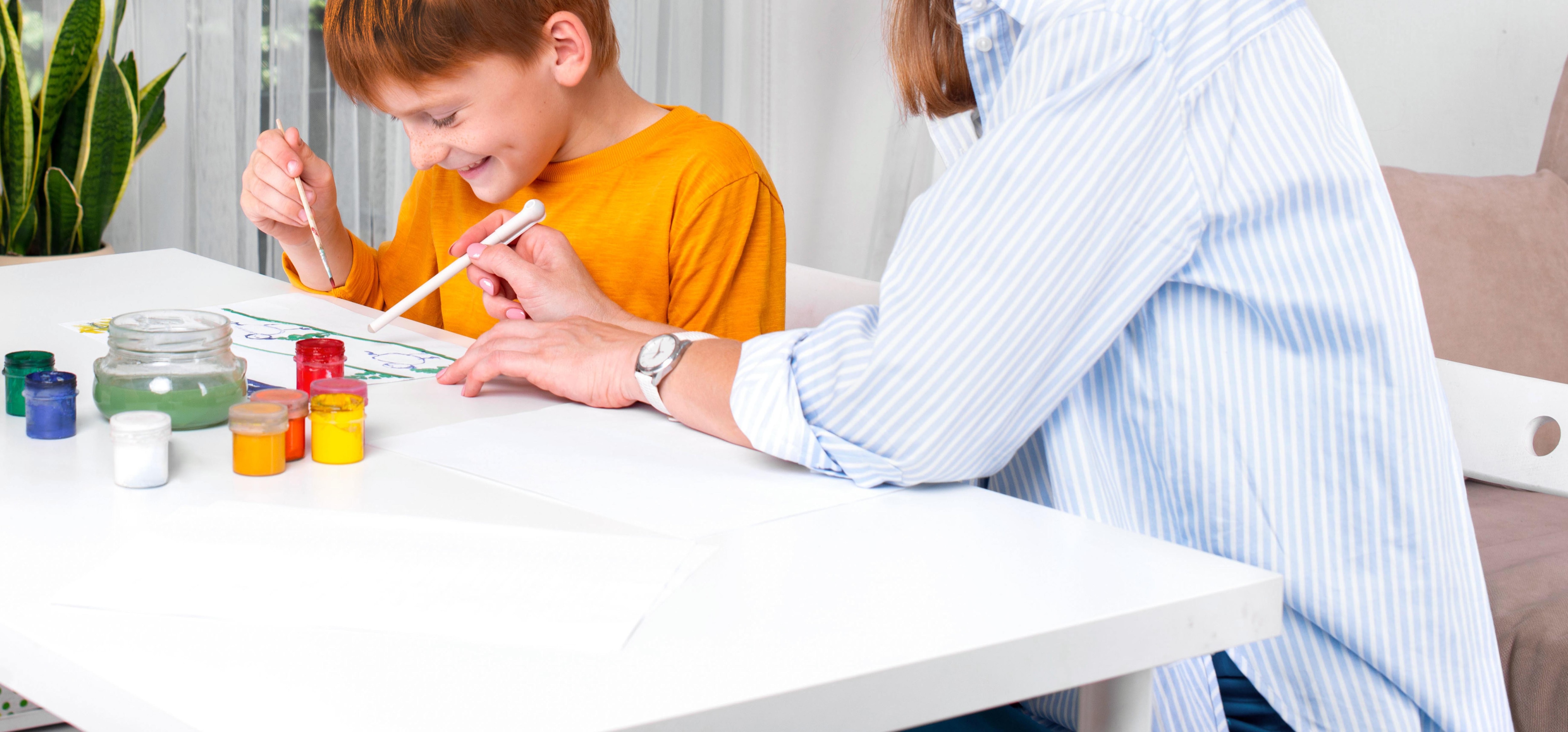 Mamá y niño divertidos  y atentos a un papel sobre la mesa.